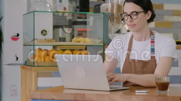 女人在电脑上打字在咖啡馆接电话视频的预览图