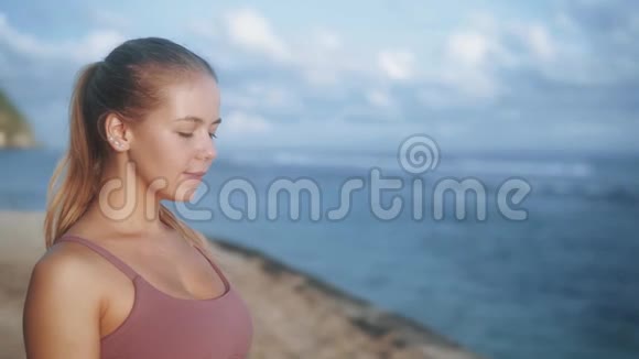 女性练习瑜伽的肖像专注于海滩呼吸慢动作视频的预览图