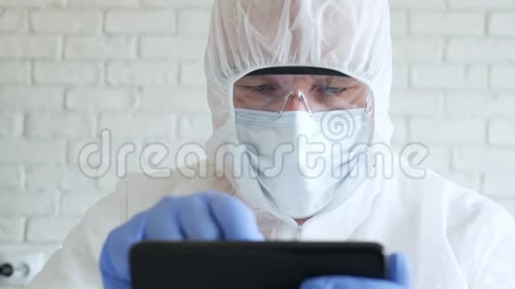 医生在医院检疫时使用手机佩戴防护服手套口罩和眼镜视频的预览图