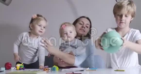 幸福家庭在家共度一天的肖像年轻的黑发母亲拿着大玩具苹果和儿子说话视频的预览图
