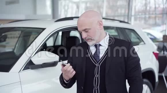一幅快乐的白种人老人的肖像在镜头前展示汽车钥匙微笑自信的富商买新的视频的预览图