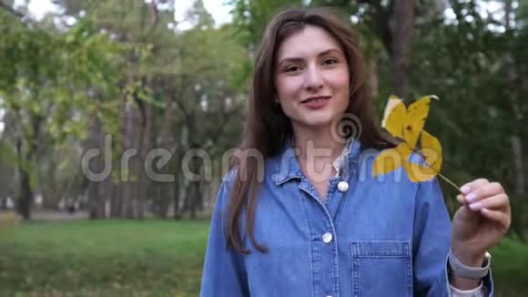一个美丽微笑的女人手里拿着一张黄色的床单的肖像中秋落叶美丽的风景视频的预览图