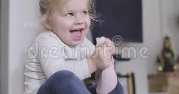 正面小女孩脱掉粉红色袜子的特写肖像白种人孩子在家享受自由时光视频的预览图