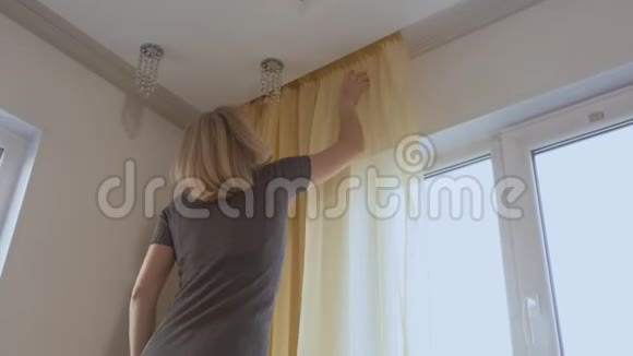 一个女人在打扫房子的时候把薄纱挂在窗户上视频的预览图