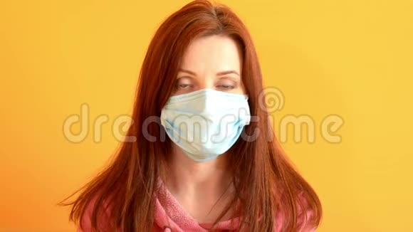 戴医用口罩的女孩用手机说话黄墙冠状病毒的流行视频的预览图