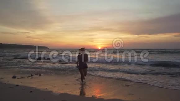 美丽的海滩上年轻快乐和兴奋的亚洲女人在巴厘岛热带海滩享受黄金时光的剪影视频的预览图