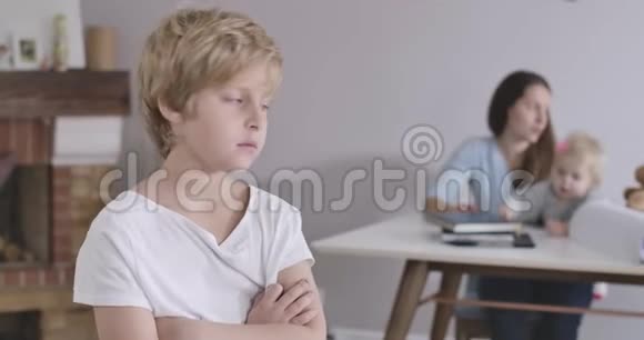 一个悲伤的白人男孩的特写灰色的眼睛回头看他的妹妹和母亲回头看盖盖视频的预览图