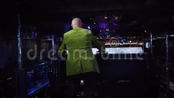 老白种人穿着绿色夹克的背景音乐和舞蹈在夜总会工作的成熟男性DJ视频的预览图