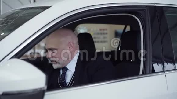 侧面肖像满意的高级白种人男子打开发动机在新的白色汽车有自信有钱的客户视频的预览图