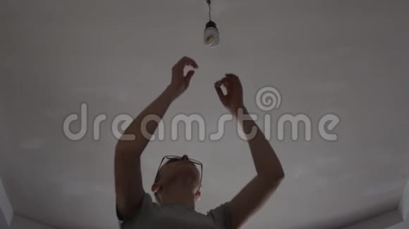 在一个黑暗的房间里一个女人用一盏新的LED了一盏节能灯视频的预览图