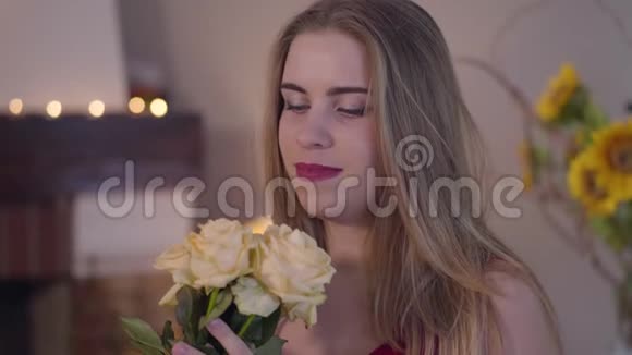 迷人的白种人黑发女人的特写肖像闻着黄色玫瑰花束对着镜头微笑快乐视频的预览图