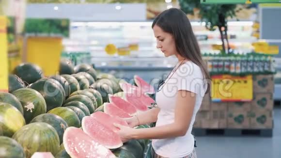 年轻的旅游妇女在超市里挑了一半西瓜闻了闻拿了下来视频的预览图