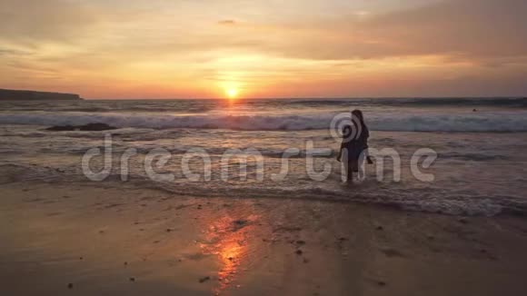 美丽的海滩上年轻快乐和兴奋的亚洲女人在巴厘岛热带海滩享受黄金时光的剪影视频的预览图