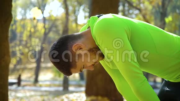 运动青年在秋季公园慢跑后休息视频的预览图