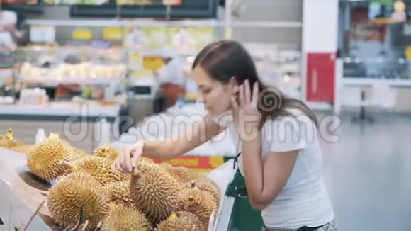 年轻的旅游妇女在杂货店挑选成熟的水果闻一闻就吃了一个视频的预览图