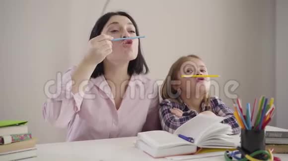 快乐的白人母女在做作业的时候玩得很开心积极的成年妇女和小女孩视频的预览图
