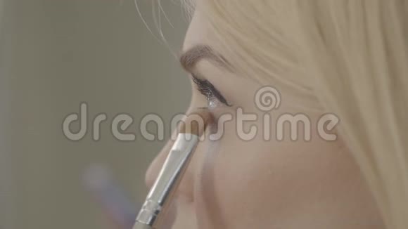 年轻白人金发女人用刷子化妆的特写镜头时装模特备展侧视图视频的预览图