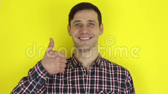 有趣的帅哥笑了笑露出拇指黄色背景上的肖像视频的预览图