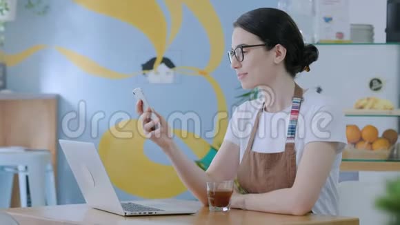 年轻女子在电脑上工作在咖啡馆里用电话视频的预览图
