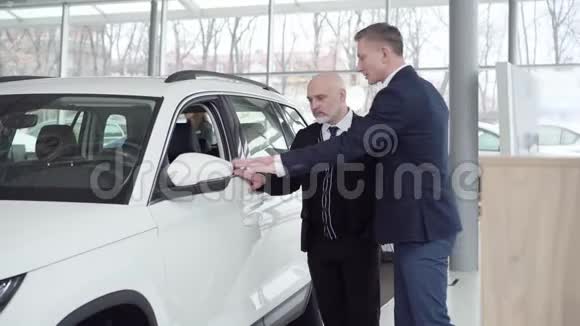 成人白种人交易员咨询汽车经销商的成功客户秃头的资深人士选择新汽车视频的预览图
