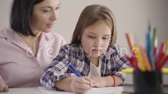 一位黑发白种人妇女的特写镜头她和女儿坐在桌子旁口述明智的父母帮助女学生视频的预览图