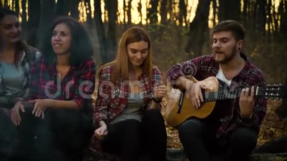 在黑暗的森林里篝火边用吉他唱着歌令人愉快视频的预览图