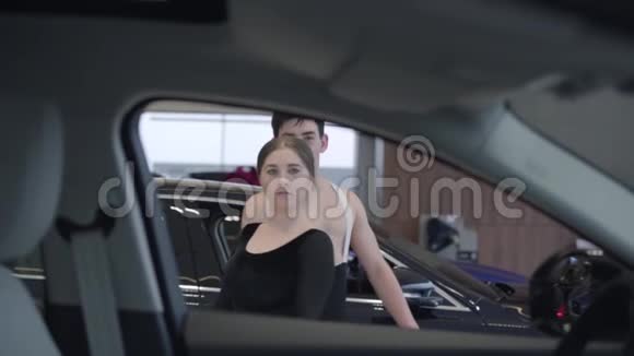 两个年轻的白种人舞者旋转着看着镜头男女在汽车经销店跳芭蕾视频的预览图