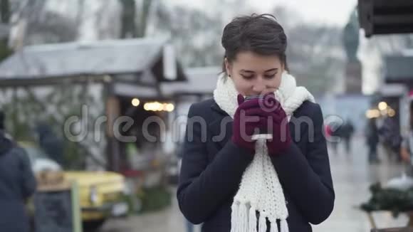 迷人的白种人年轻女子站在冬天的街道上喝着咖啡微笑着快乐的女孩视频的预览图