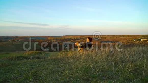 女孩和美国斯塔福德郡的猎犬在乡下的青山上休息视频的预览图
