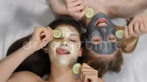 微笑的女性bst朋友玩切好的黄瓜片同时涂粘土面膜隔离射击白色视频的预览图
