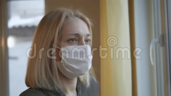 一个戴着医用口罩的女人看着窗外视频的预览图
