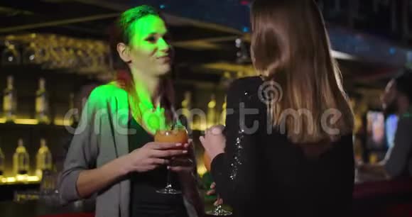 两个快乐的年轻白种人女人在夜总会里用鸡尾酒跳舞和聊天快乐的女孩子视频的预览图