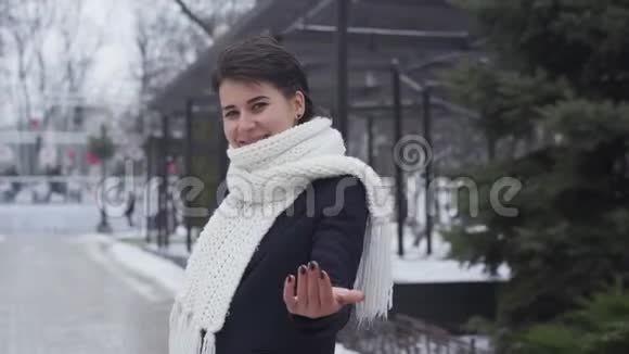 微笑的白人女孩走在冬天的街道上穿着白色围巾和外套的漂亮年轻女人享受寒冷的一天视频的预览图