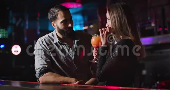 年轻迷人的高加索女人喝鸡尾酒和英俊的中东男人在夜总会交谈很漂亮视频的预览图