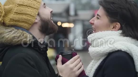 近距离侧面看笑白种人夫妇拿着咖啡杯年轻男女站在户外聊天视频的预览图