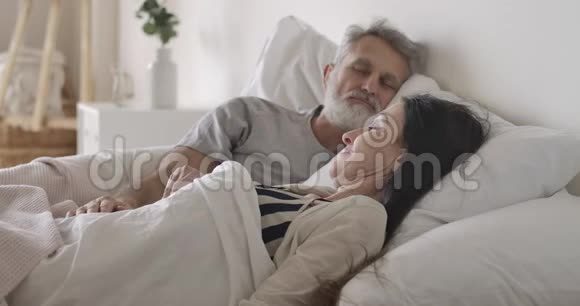 侧视特写白种人女人早上在床上伸展熟睡的丈夫拥抱可爱的妻子快乐视频的预览图