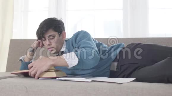 精疲力竭的白人年轻人看书打哈欠戴眼镜的成年大学生睡着了视频的预览图