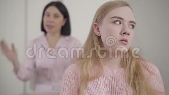 一个年轻的白种人女孩的特写镜头听着成年黑发女人在后台大喊大叫令人厌烦的母亲视频的预览图