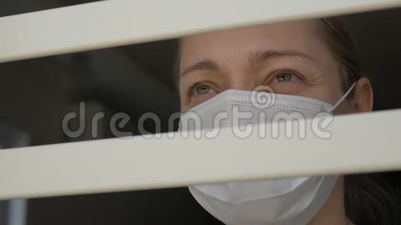 一个戴着医用口罩的女人从窗外透过铁栏看着视频的预览图