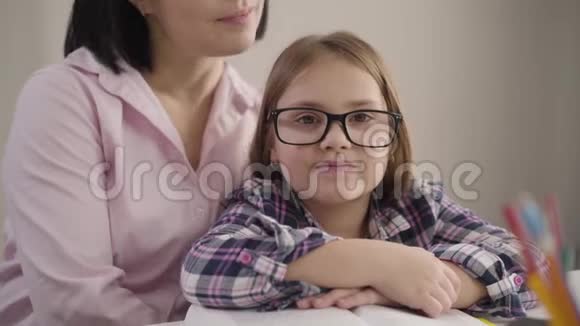 特写肖像快乐的白种人女孩戴着眼镜看着相机微笑年轻的母亲爱抚女儿视频的预览图