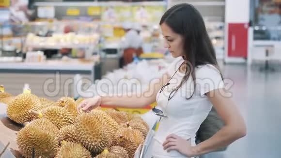 年轻的旅游妇女在杂货店挑选成熟的水果闻一闻就吃了一个视频的预览图
