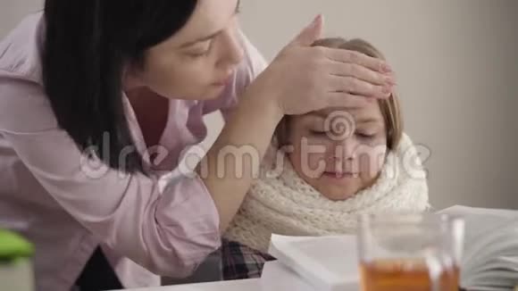 棕发白种人母亲检查女儿的体温我漂亮的女学生坐在桌子旁视频的预览图