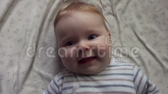 幸福的蓝眼睛宝宝躺在白色的毯子上视频的预览图