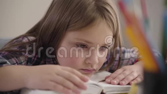 一个美丽的白种人黑发女孩的特写棕色的眼睛在书上昂首疲惫的女学生看着休息视频的预览图