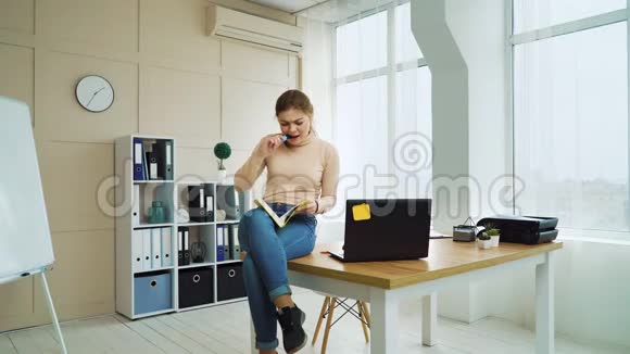 成功的商业女性坐在桌子上写着笔记本视频的预览图