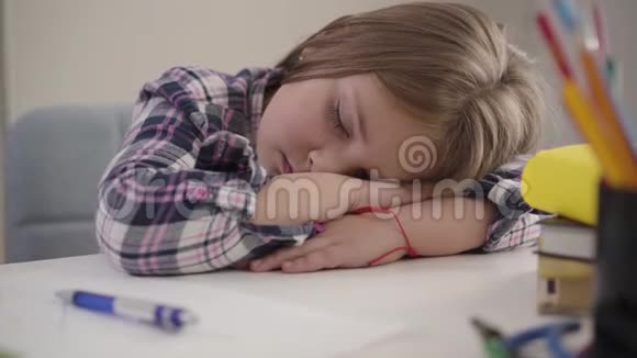 摄像机从左到右围绕着熟睡的女孩移动睡在桌子旁疲惫的女学生的特写镜头超载视频的预览图