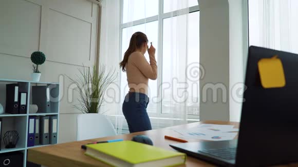 漂亮的女企业家在办公室的窗前跳舞视频的预览图
