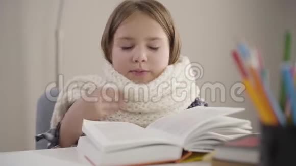 一幅迷人的白种人女孩的特写肖像她戴着白色围巾坐着看书打喷嚏我的女学生视频的预览图
