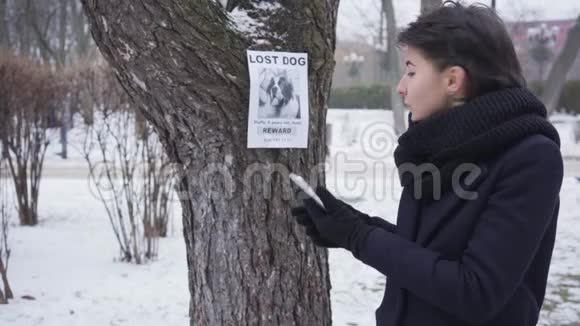 侧面看微笑的白种人女孩打电话号码写的失踪狗广告快乐的女人找到丢失的宠物视频的预览图