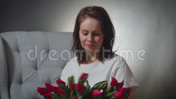 一位美女在椅子上闻着一束红色郁金香视频的预览图